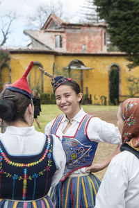 Portrait of a smiling young woman standing against building