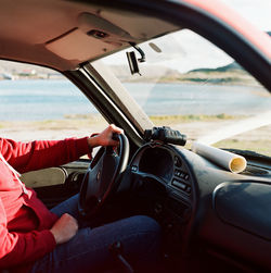 A man sits at the wheel of a car with a map and binoculars