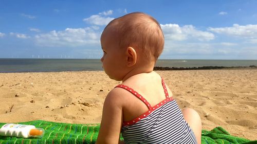 Rear view of boy on beach against sky