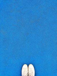 Low section of man standing on blue floor