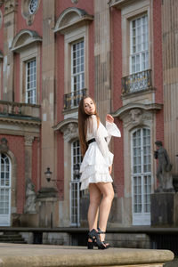 Portrait of a smiling young woman in front of building