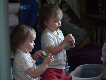 Twin 3 year old girls playing inside.