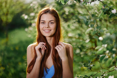 Portrait of young woman standing against plants