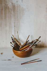 High angle view of paintbrushes in bowl on table