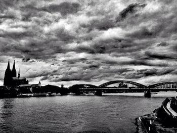 Bridge over river against cloudy sky