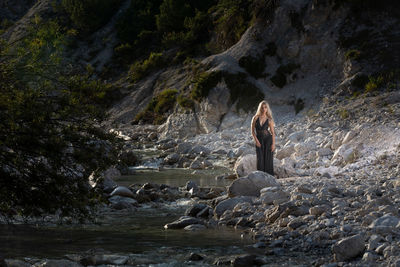 Woman sitting on rock by waterfall