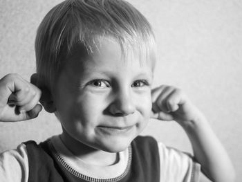 Portrait of boy smiling while plugging ears
