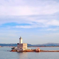 Lighthouse by sea against sky