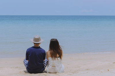 Rear view of women at beach against sky