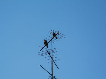 Low angle view of communications tower against clear blue sky