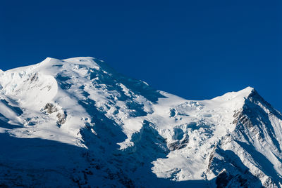 Snow covered mountains against clear blue sky