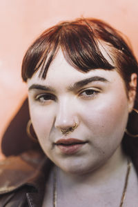 Woman wearing nose ring against wall