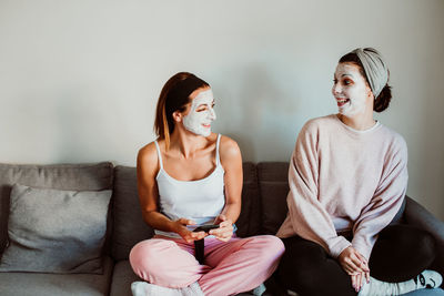 Women with facial mask sitting on sofa at home