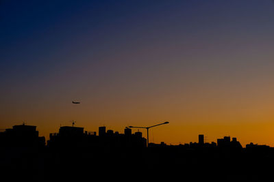 Silhouette city against orange sky