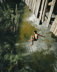 Full length of shirtless man in lake at forest