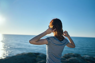 Woman standing at sea shore against sky