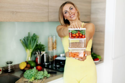 Containers with vegetables and buckwheat in the hands of a young woman. 