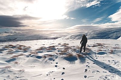 Rear view of man standing on snow covered landscape