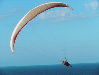 Man paragliding over sea against clear blue sky