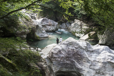 Man standing on rock against waterfall in forest