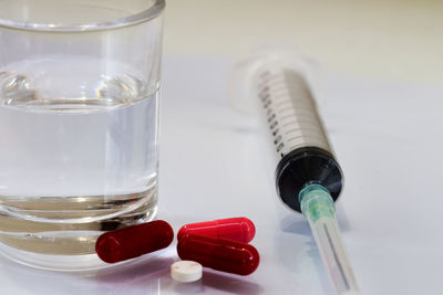 Close-up of pills with syringe on table