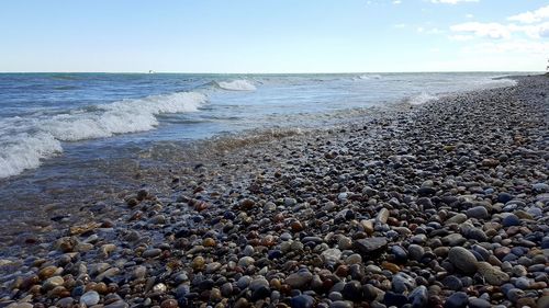 Surface level of pebble beach against clear sky