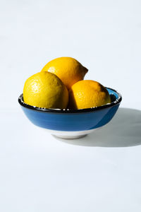 Close-up of lemons in bowl on white background