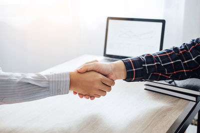 Cropped image of businessmen handshaking over desk