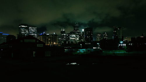 Illuminated buildings in city against sky at night
