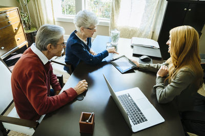 High angle view of financial advisor explaining plan to senior couple on tablet computer in office