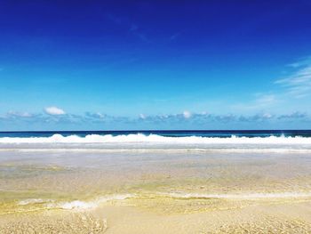 Scenic view of beach against blue sky