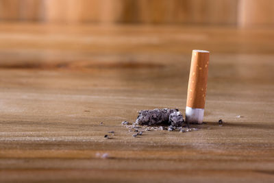 Close-up of burning cigarette on table