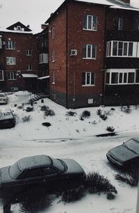 Snow covered houses by building in city