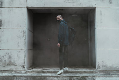 Full length of man standing against wall of building