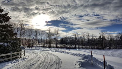 Scenic view of snowy landscape against cloudy sky on sunny day