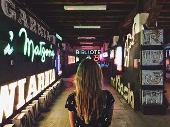 Rear view of woman standing on illuminated underground walkway