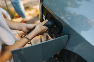 High angle view of boy inserting plug while charging electric car