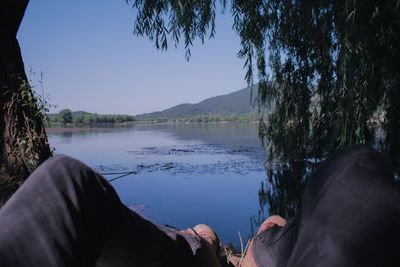 Low section of man on lake against sky
