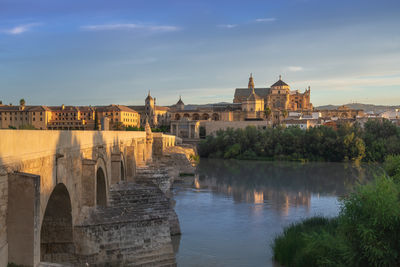 Buildings by river against sky