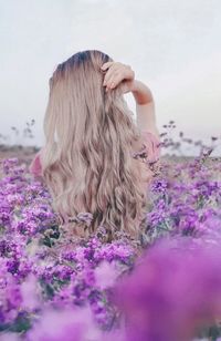 Woman standing by purple flowering plants