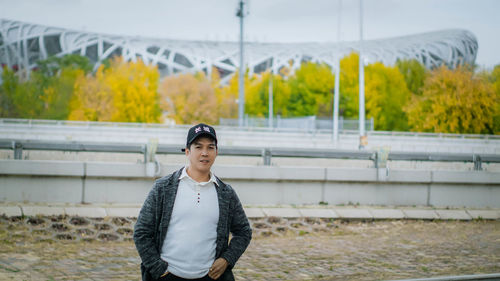 Portrait of young man standing against wall