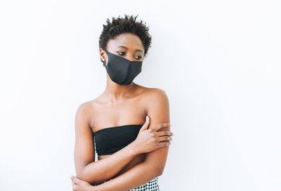 Beautiful young african american woman in black top and the face mask isolated on white background