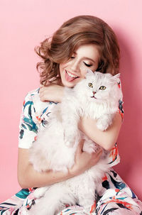 Portrait of a smiling young woman with cat against gray background