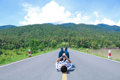 People riding bicycle on road by mountain against sky