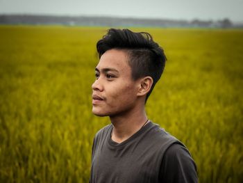 Portrait of young man looking away on field