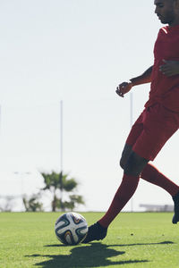 African american male soccer player practicing on grass pitch