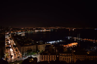 Illuminated buildings in town against sky at night