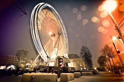 People in illuminated city against sky at night