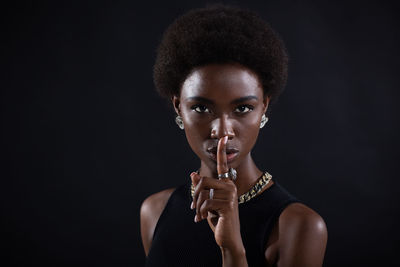 Portrait of young woman holding mask against black background