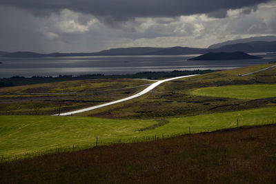 Scenic view of landscape and road against lake and sky